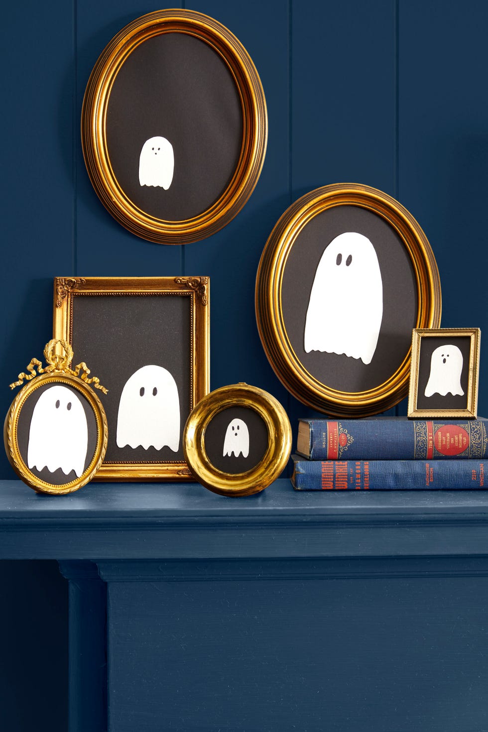 a grouping of simple white ghosts shapes on black paper inside gold colored frames