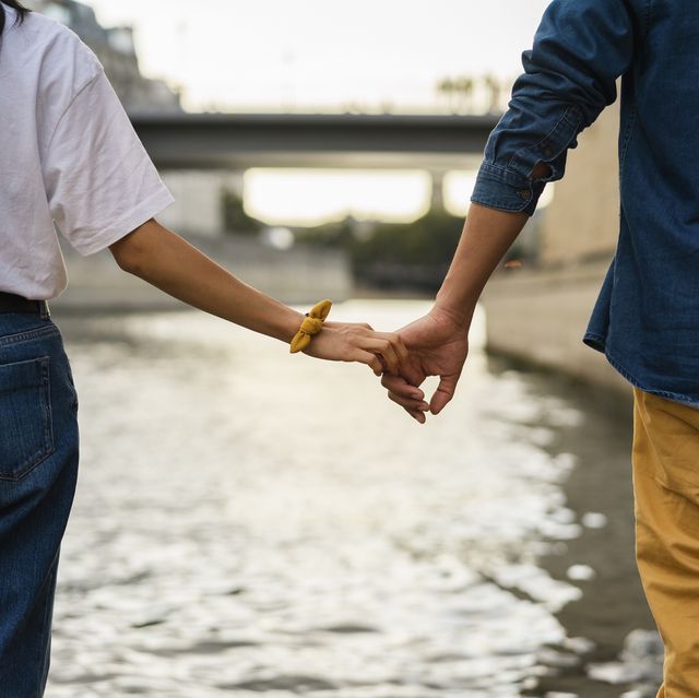france, paris, couple holding hands at river seine