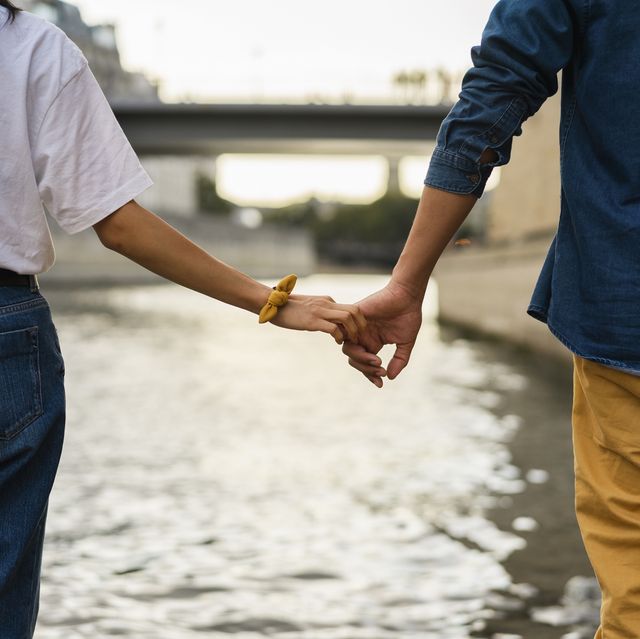 france, paris, couple holding hands at river seine