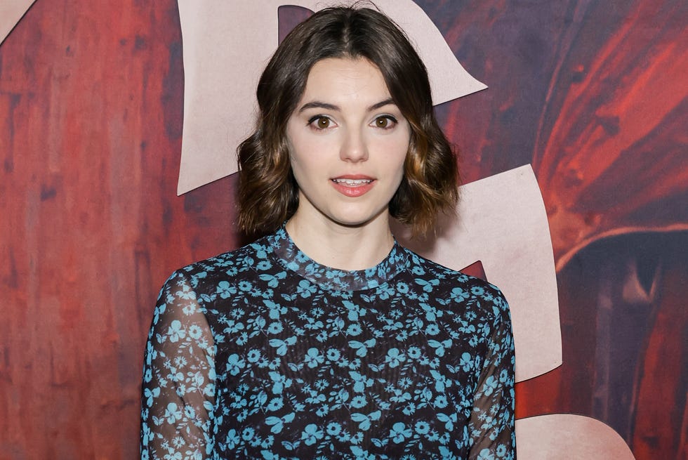 francesca reale, a young woman wearing a black and blue floral dress standing looking at the camera, short brown hair worn in lose waves