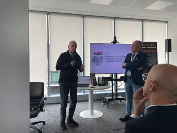 a presentation in an office setting featuring two speakers and a display screen