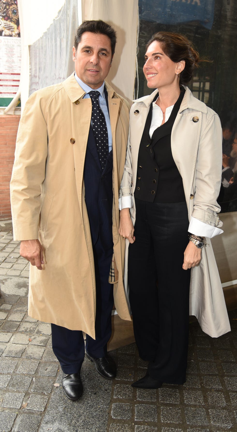 la pareja, ambos con gabardina, posan en las calles de sevilla