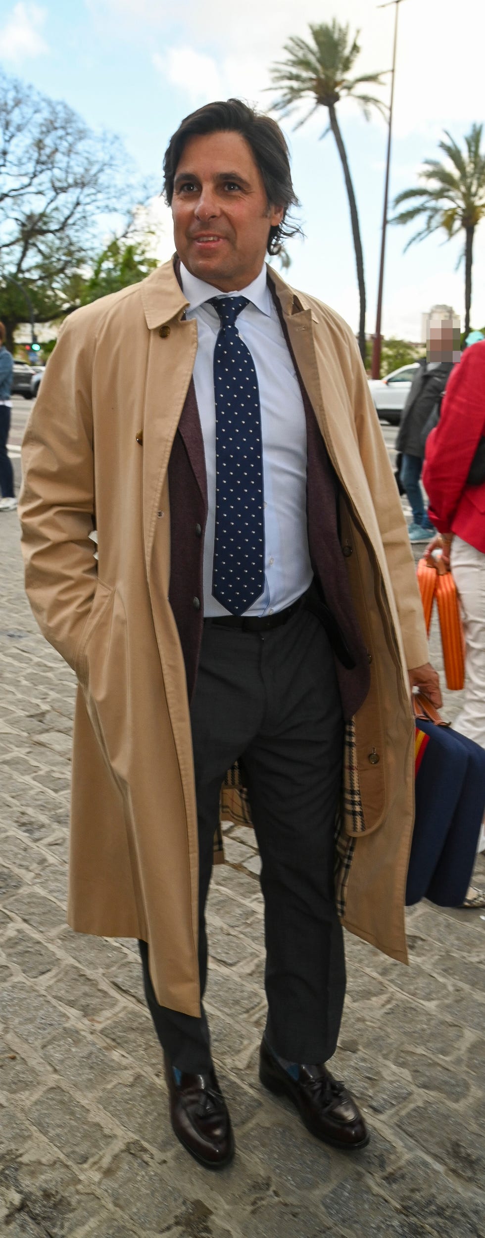 el torero, con traje y gabardina, a su llegada a la plaza de toros de sevilla