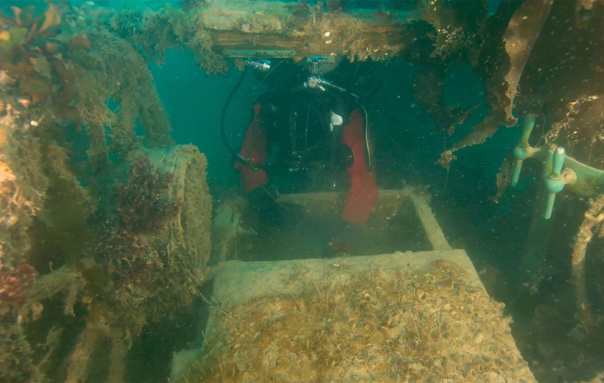 Om de lagere dekken van de HMS Terror te onderzoeken laat een archeoloog van Parks Canada een kleine ROV door een dekluik zakken