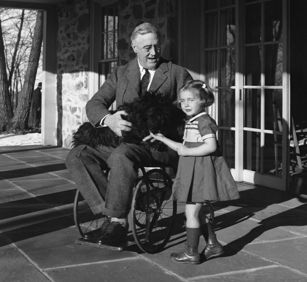 Franklin Roosevelt holds his Scotch terrier, Fala, on his lap as he talks to Ruthie Bie, the daughter of the Hyde Park caretaker