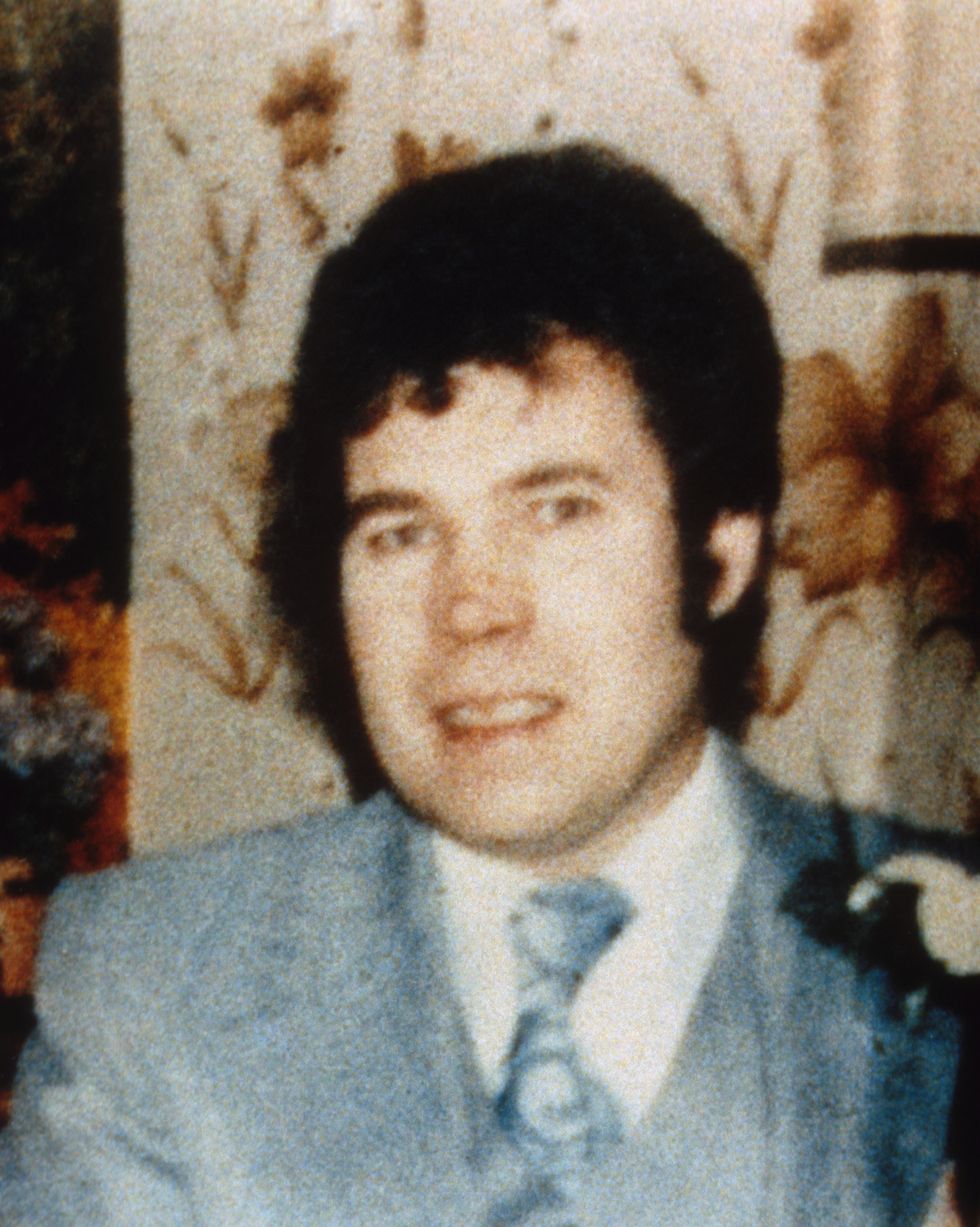 a man in a blue suit jacket and tie with a white collared shirt smiles at the camera