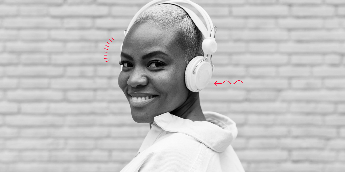 woman smiling at the camera wearing headphones listening to an audiobook