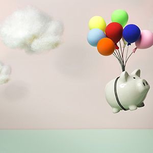piggy bank lifted by colourful balloons on pink background