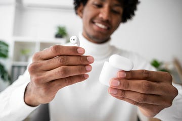 freelancer holding wireless in ear headphones at home office