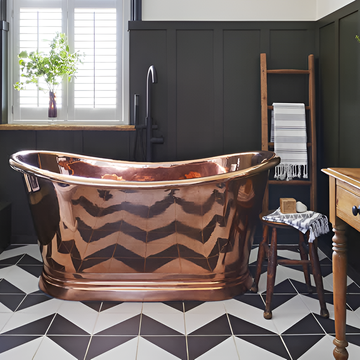 a large copper freestanding bathtub in a bathroom with wall panelling and monochrome, black and white, floor tiles