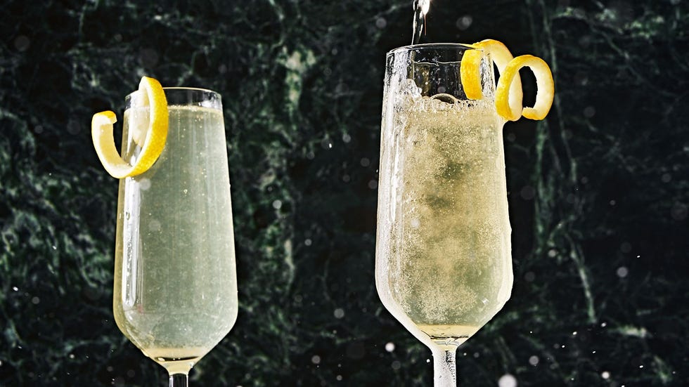 two champagne flutes filled with a french 75 and garnished with a lemon twist