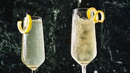two champagne flutes filled with a french 75 and garnished with a lemon twist