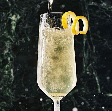 two champagne flutes filled with a french 75 and garnished with a lemon twist