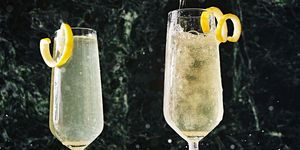 two champagne flutes filled with a french 75 and garnished with a lemon twist
