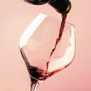 french dry red wine, pours into glass, trendy pink background, space for text, selective focus