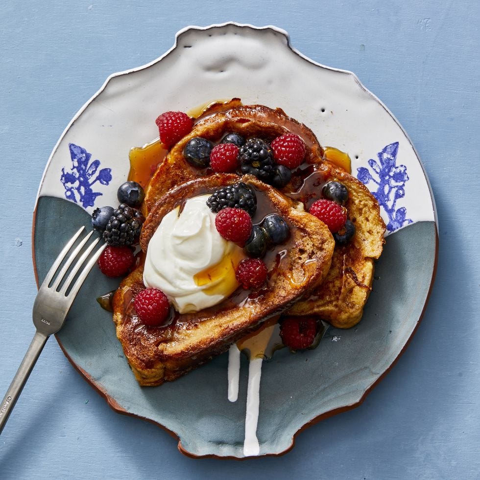 french toast with berries, cream and syrup on top