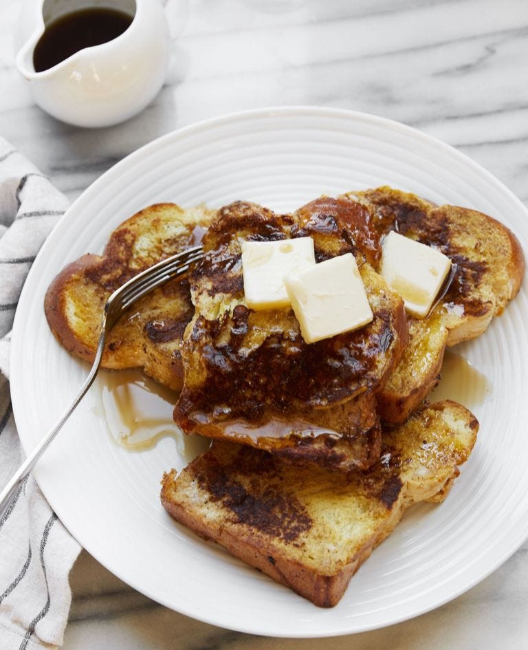 french toast on a plate topped with maple syrup and pats of butter