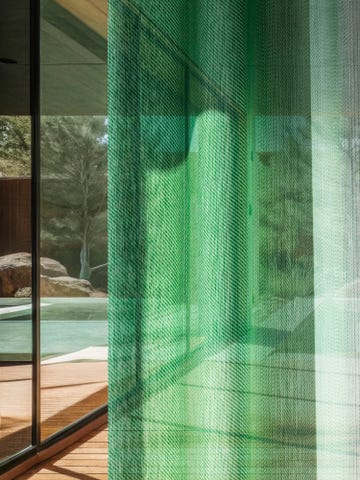 translucent green fabric curtain filtering light and revealing a view of the outdoors