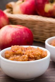 Fresh applesauce in bowls and red apples