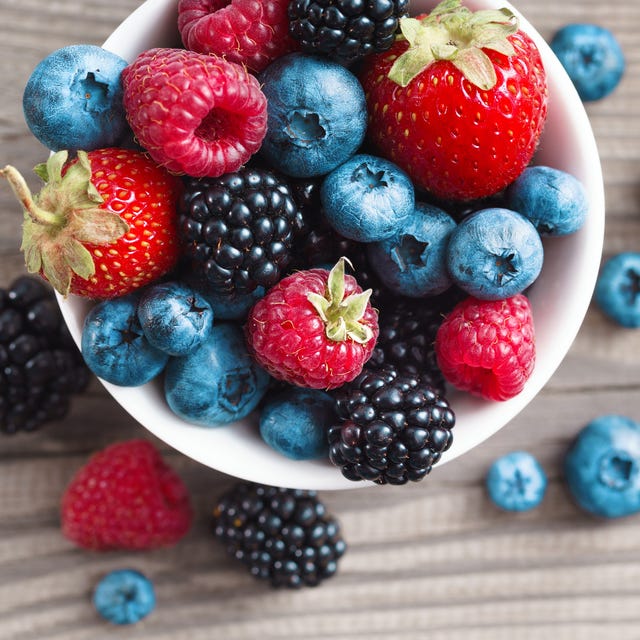 fresh berries in a basket on rustic wooden background