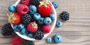 fresh berries in a basket on rustic wooden background