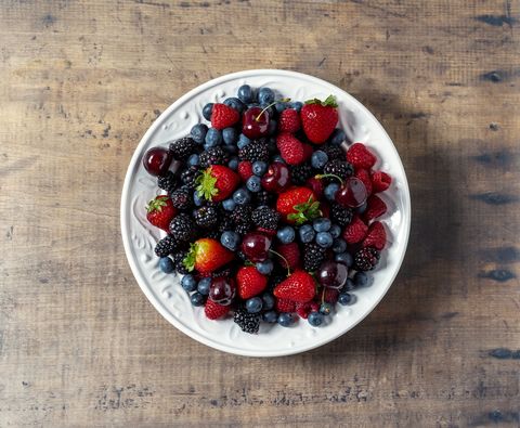 fresh berries in a bowl on wooden background
