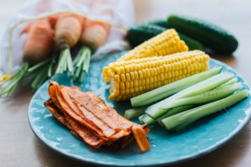 fresh cooked carrot bacon lies on a turquoise plate with corn and cucumber meat replacement, snack