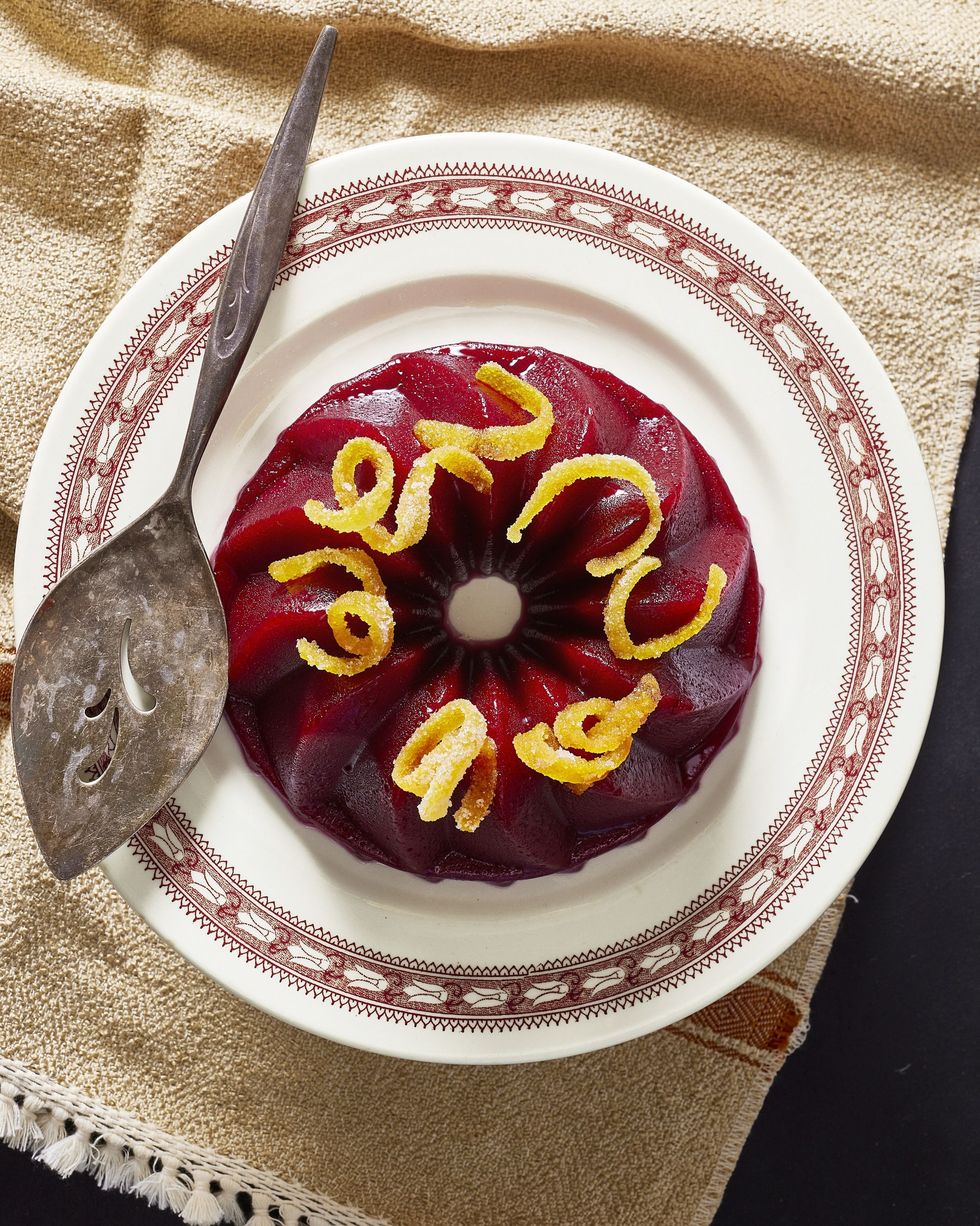 molded cranberry sauce on a serving plate with candied orange zest