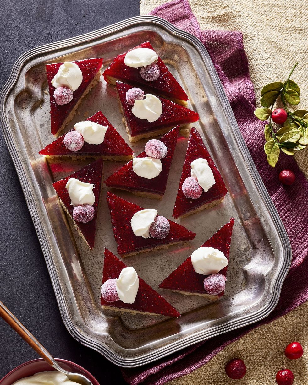 cranberry walnut shortbread bars cut into triangles and arranged on a silver serving tray