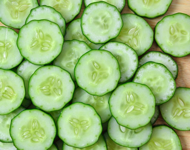 pepino fresco y rebanadas sobre fondo blanco