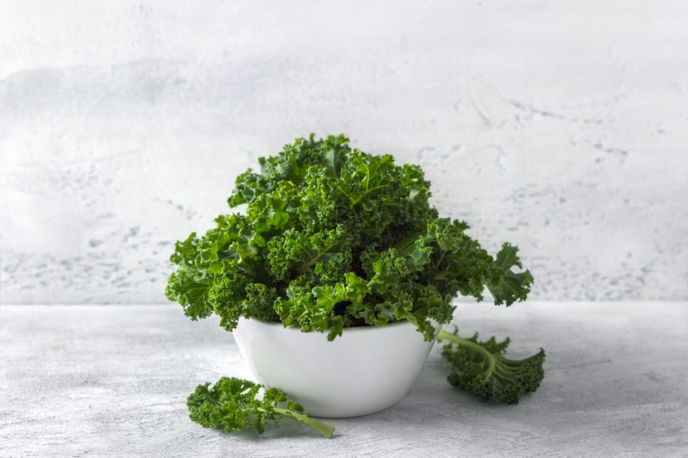 fresh curly kale salad in a white ceramic bowl on a light gray background