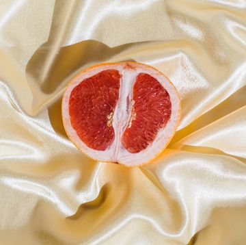 fresh grapefruit on beige soft silk fabric background sex concept women's health, sexuality, erotic tension female vagina and clitoris symbol