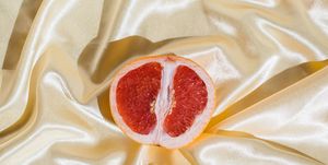 fresh grapefruit on beige soft silk fabric background sex concept women's health, sexuality, erotic tension female vagina and clitoris symbol