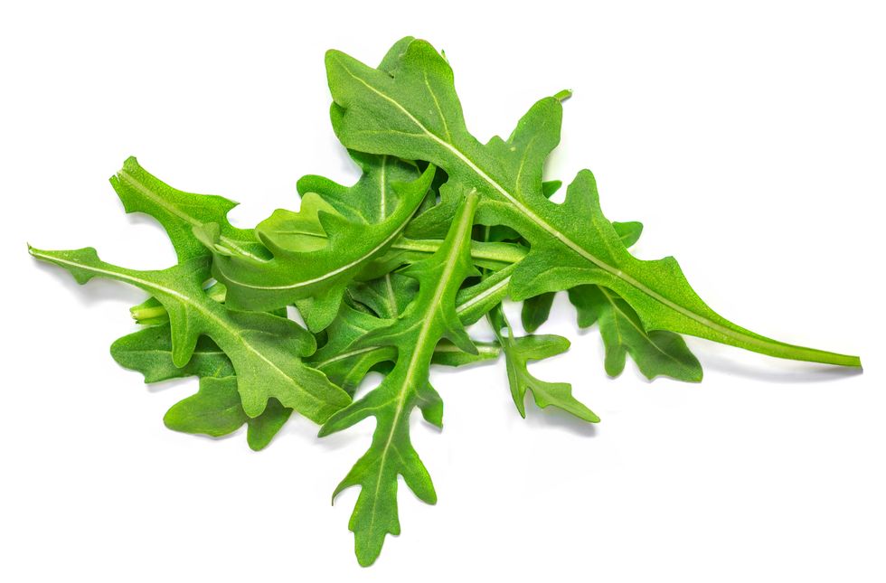fresh green arugula leaves isolated on white background, top view, flat lay pile of ruccola