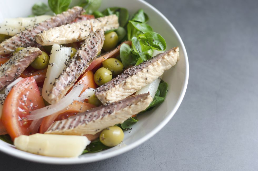 a mackerel salad in a white bowl on a grey countertop.