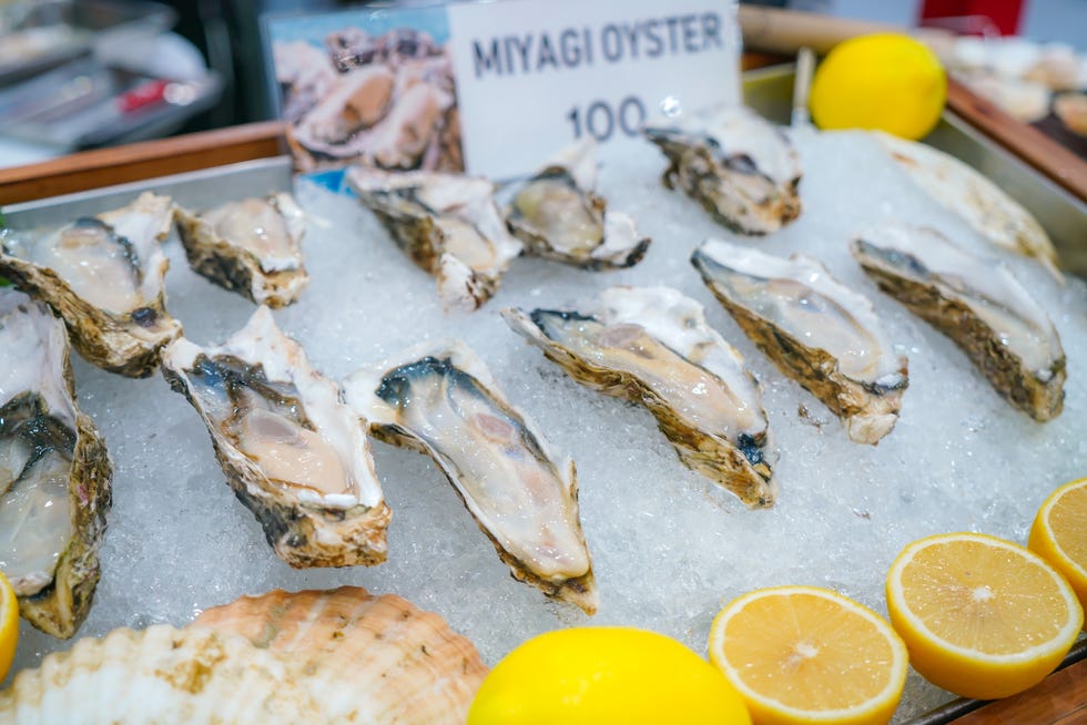 fresh opened oyster with sliced lemon offered as top view on crushed ice