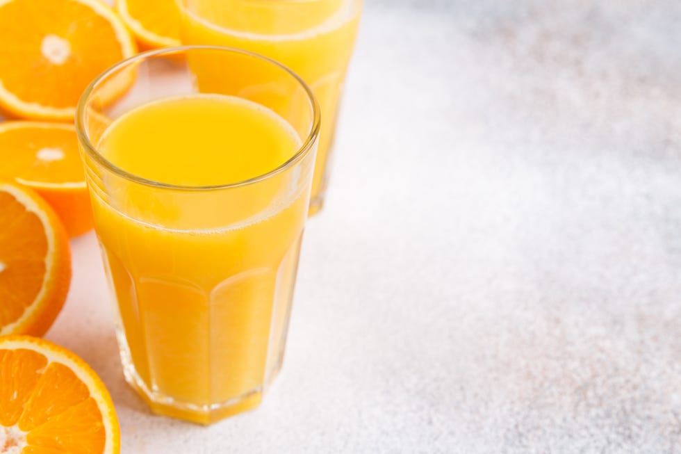 fresh orange juice and oranges on light background