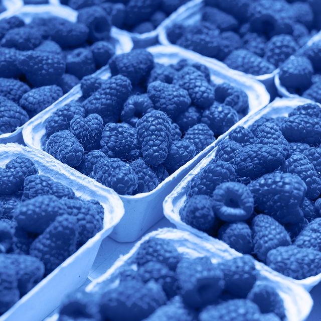 fresh raspberry on a market in paper box containers photographed at an angle from above, image monochrome toned color of the year beautiful blue background for design