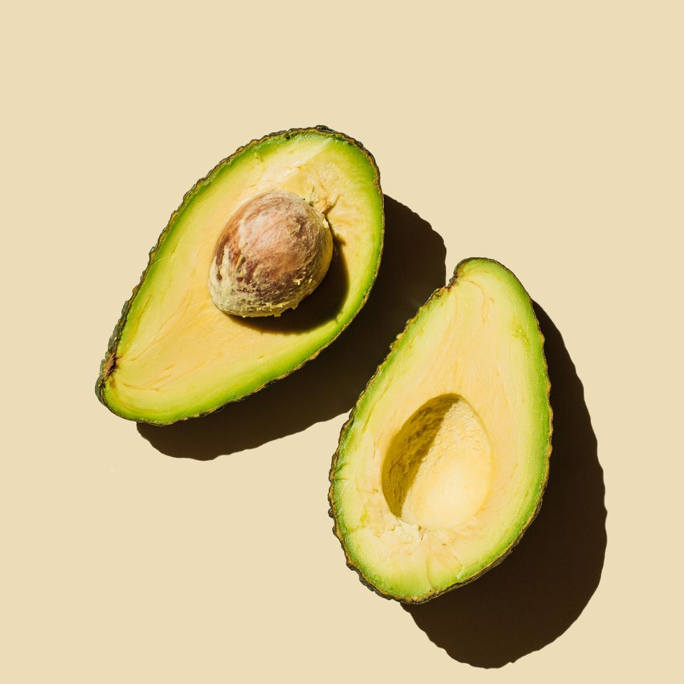 fresh ripe green avocado fruit halves on beige background. healthy food, diet and detox concept. flat lay, top view, copy space