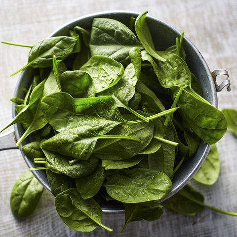 fresh spinach leaves in colander on wood