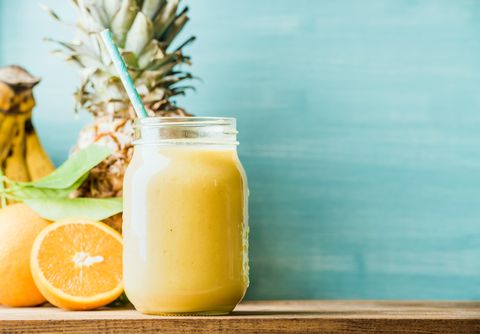 freshly blended yellow and orange fruit smoothie in glass jar