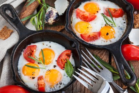 Fried eggs with tomatoes in frying pans served for breakfast