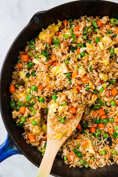 fried rice with egg, carrots, and peas, in a black cast iron skilelt