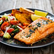fried salmon steaks, fried potatoes and fresh vegetables on wooden table, best foods for muscle recovery
