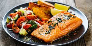 fried salmon steaks, fried potatoes and fresh vegetables on wooden table, best foods for muscle recovery