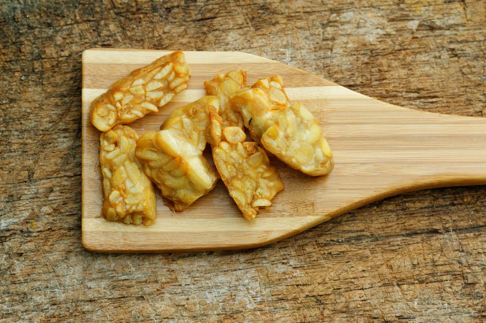 Fried Tempeh in wooden spatula on textured background