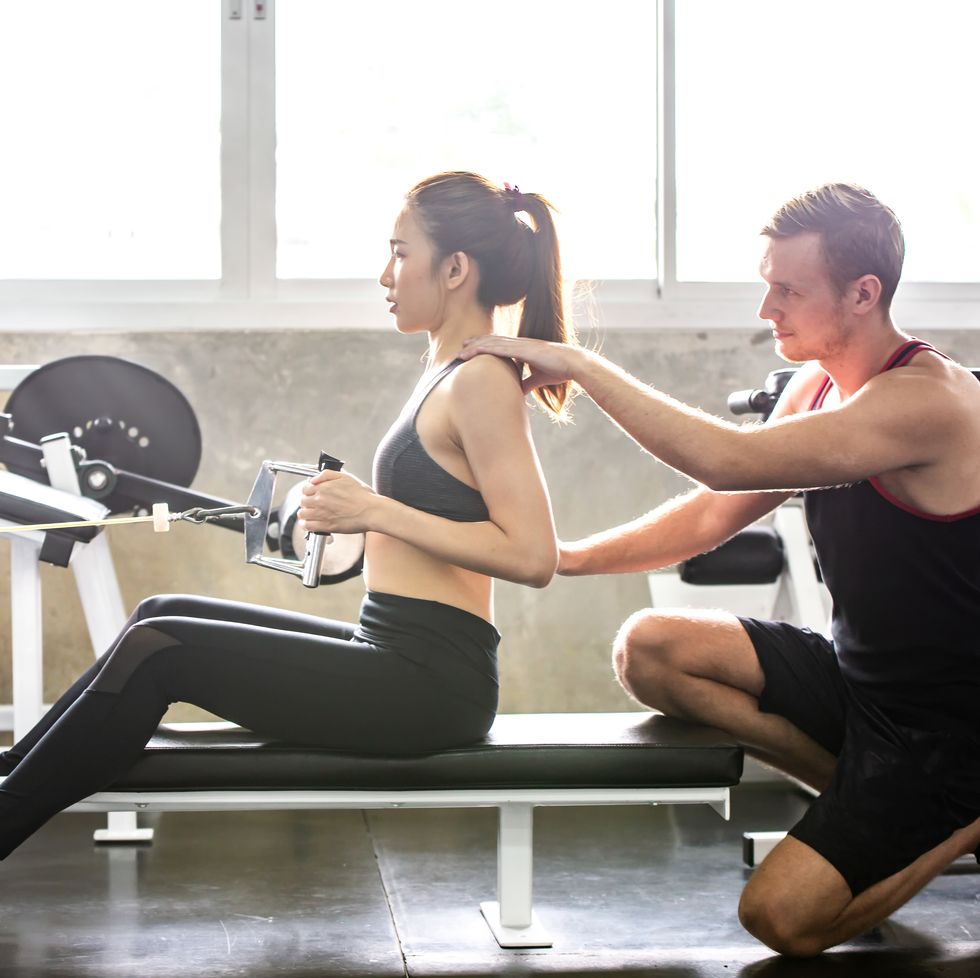 friend helping woman in exercising at gym