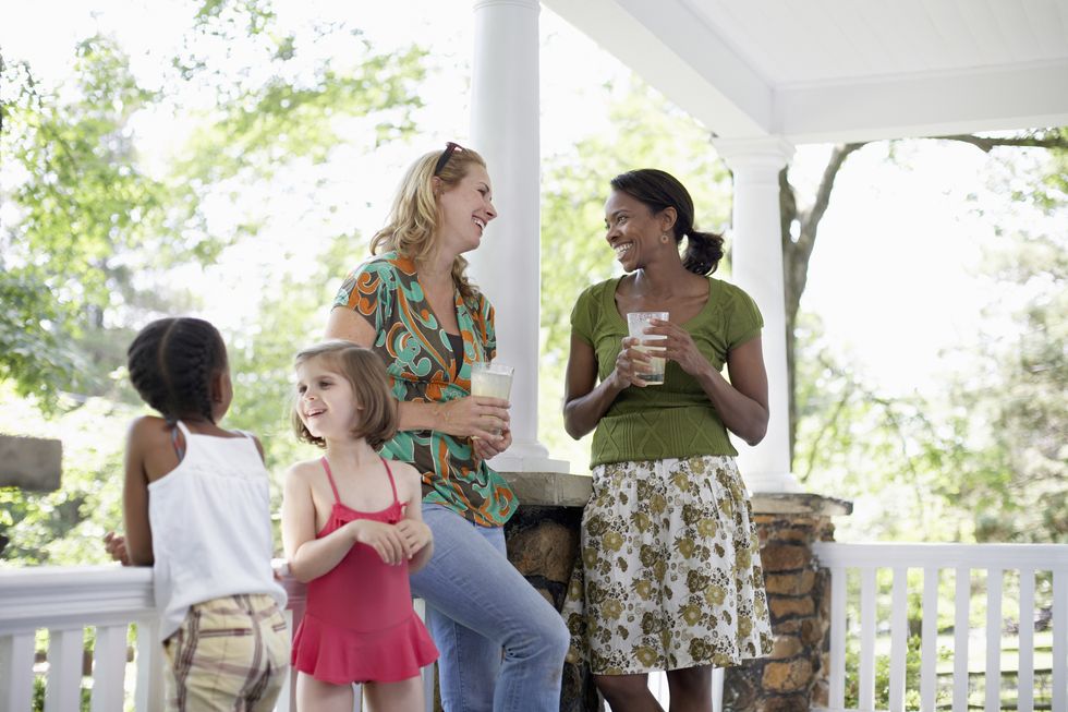 Two women and girls (7-8 years) talking on porch