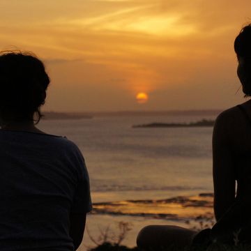 Women sitting on the beach at sunset