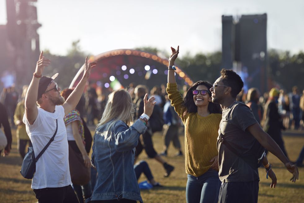 friends dancing at festival with arms in air